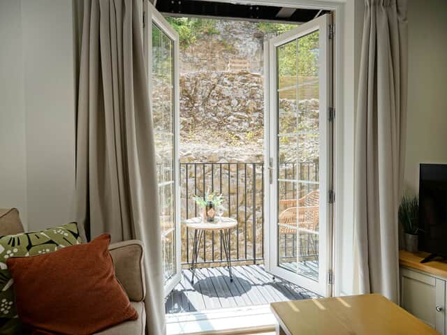 Lounge and balcony view inside Rock Mill Apartment 12 in Stoney Middleton